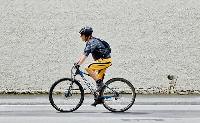 Person riding a bike wearing a backpack and helmet